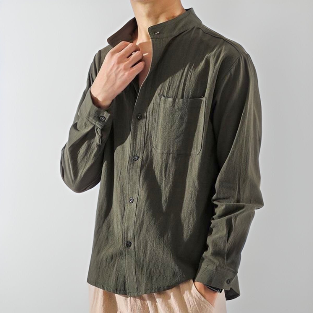 Man wearing olive green band-collar button-up shirt with relaxed long sleeves