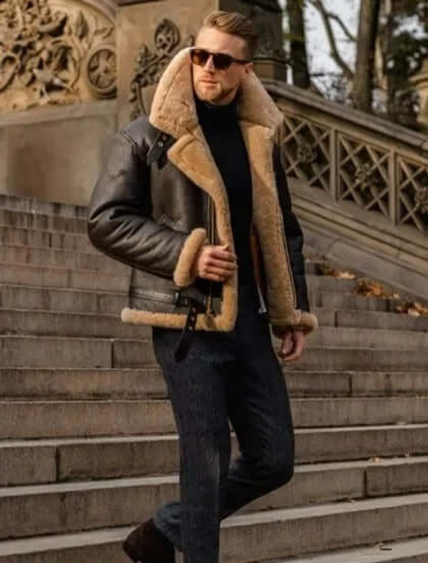 Man wearing brown shearling bomber jacket with tan fur collar on stone steps