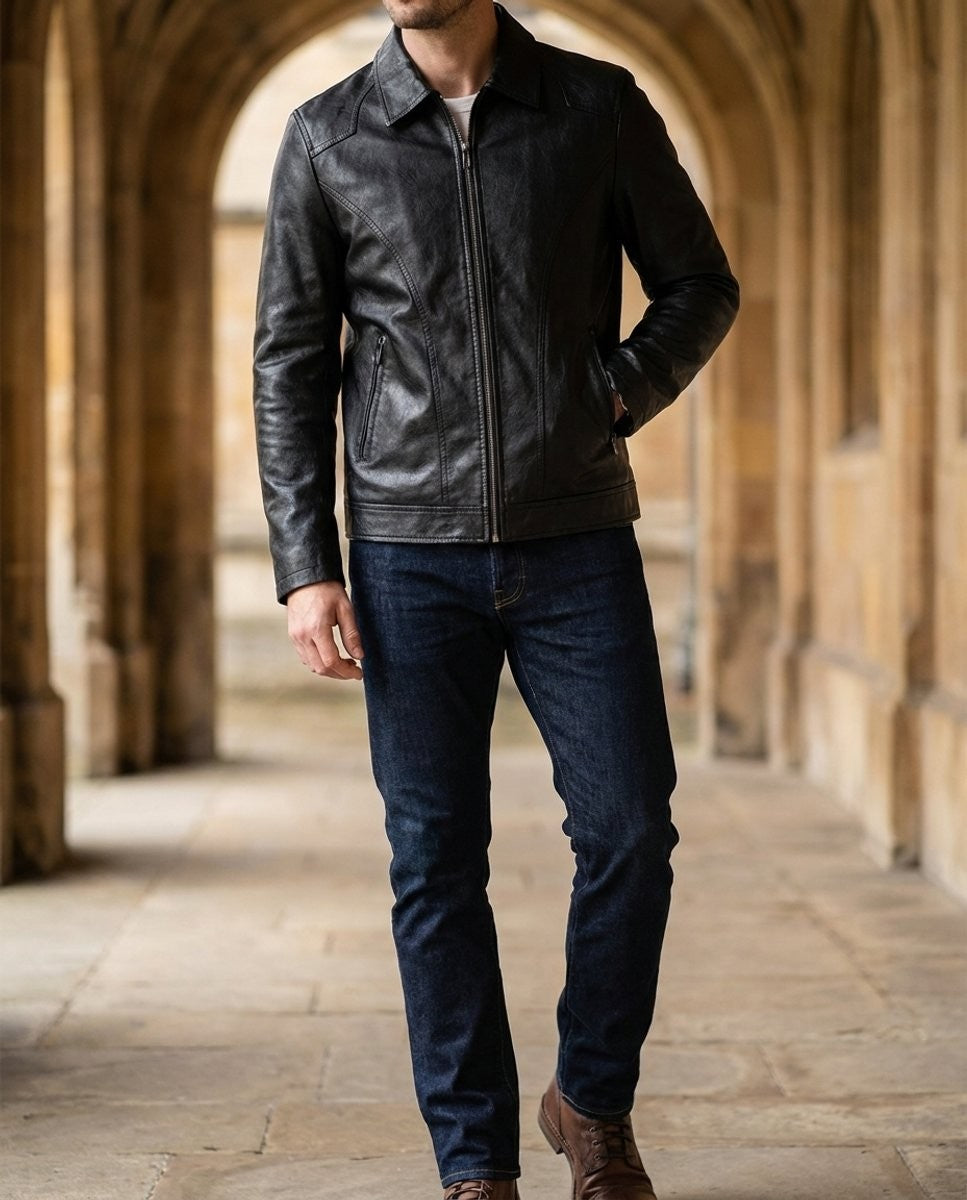 Man wearing black leather biker jacket with jeans, walking through stone archway