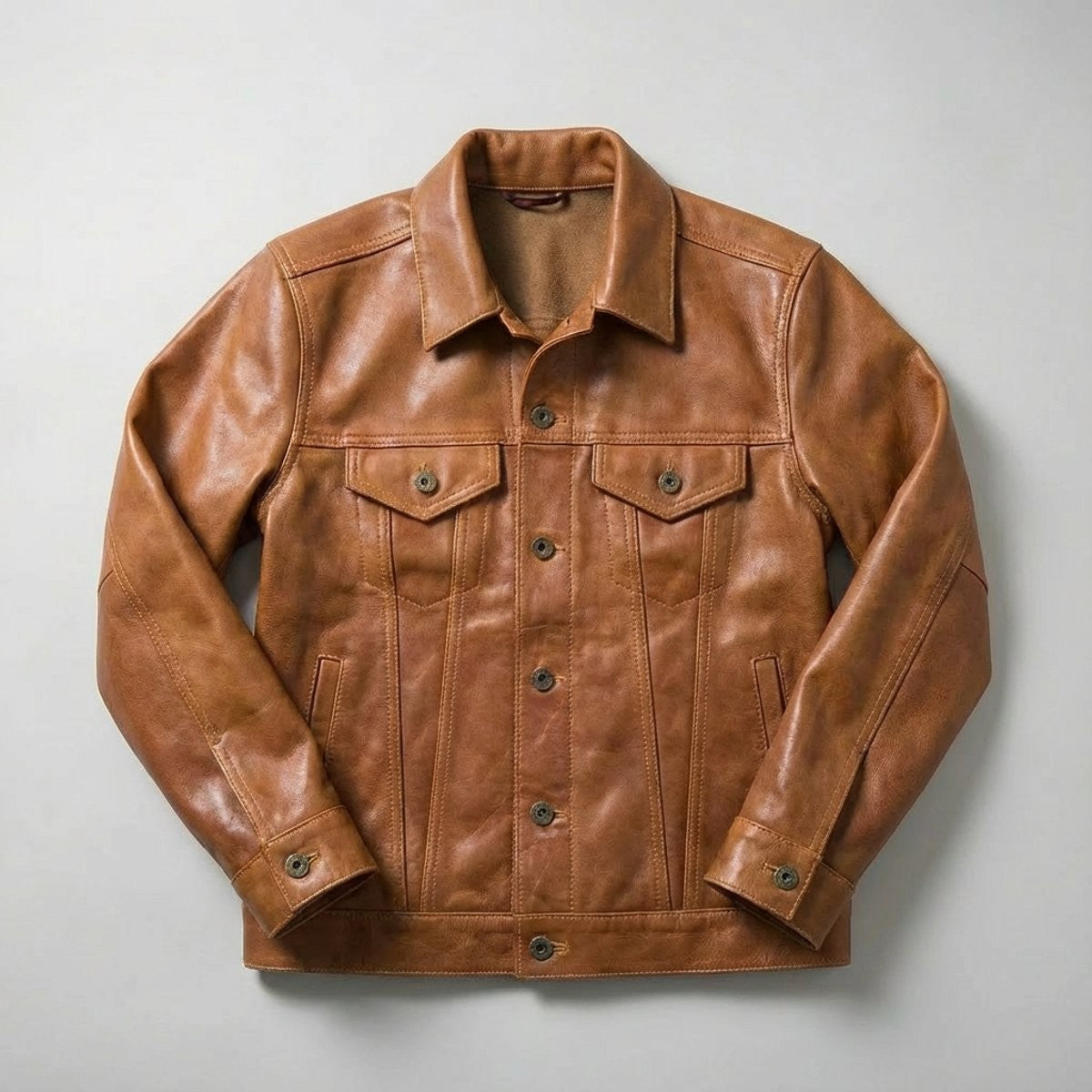 Tan full-grain leather trucker jacket with button-front fastening and chest pockets