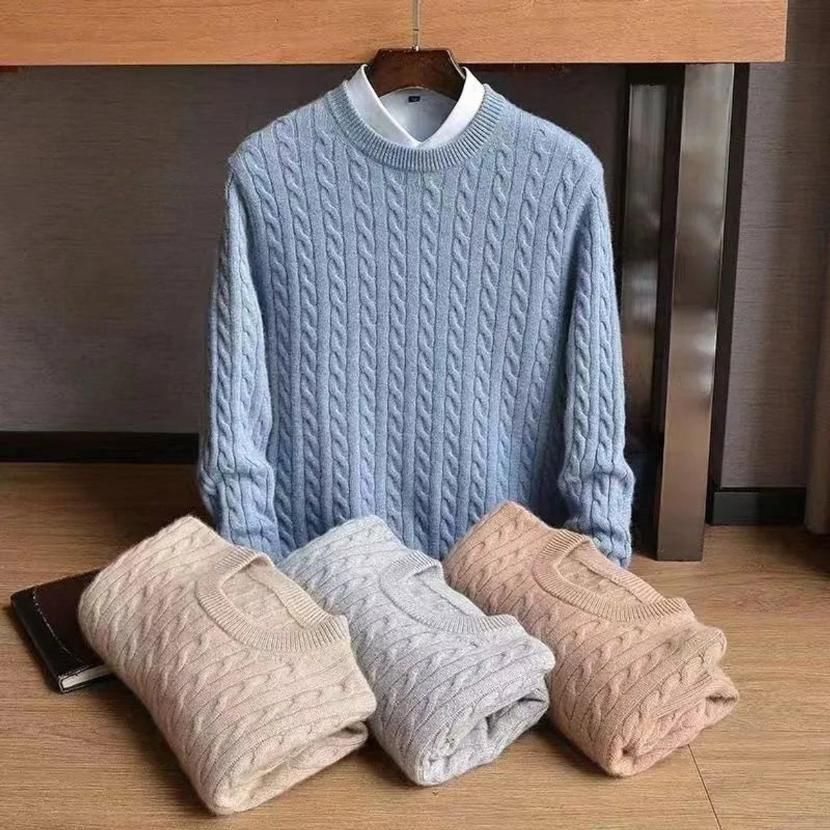 Light blue cable knit jumper on hanger with folded colour options beneath
