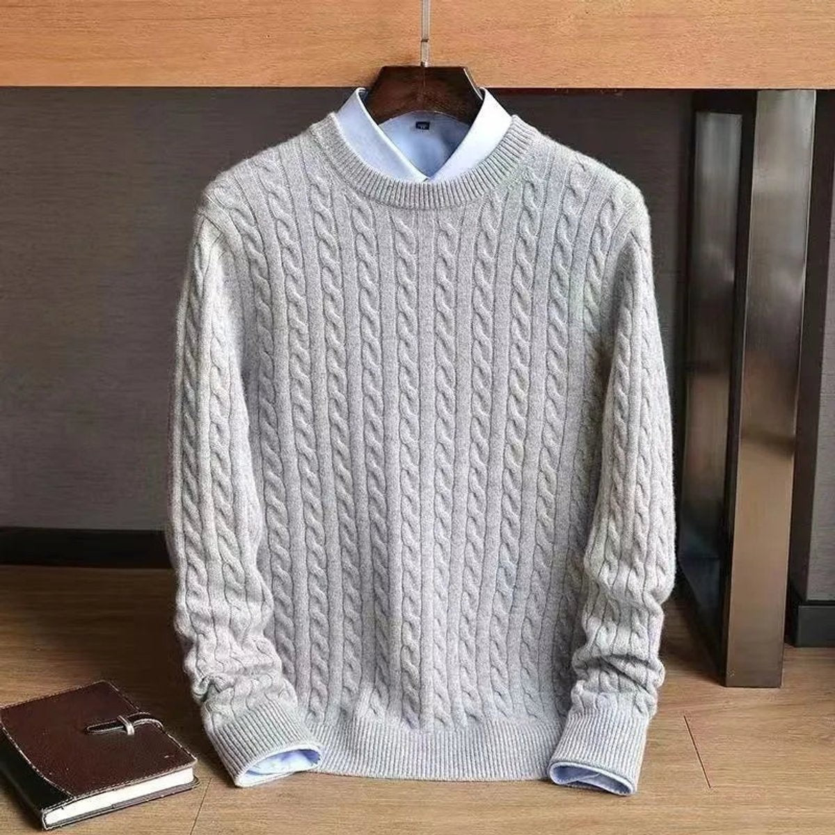 Grey cable knit crew neck jumper displayed on wooden hanger