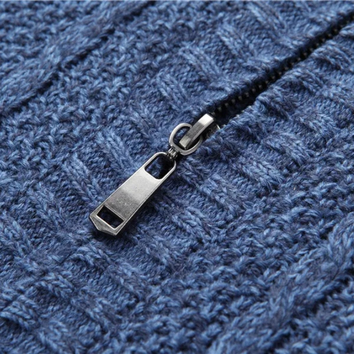 Close-up of zip pull on blue cable-knit cardigan jacket