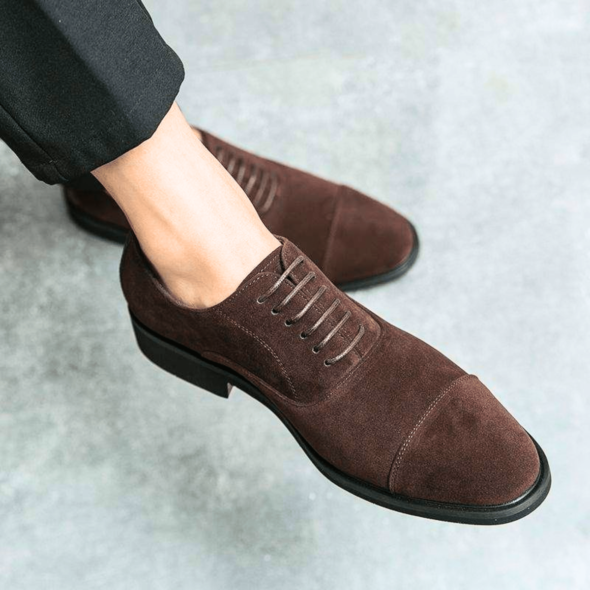 Close-up of brown suede Oxford shoe with cap toe and black sole