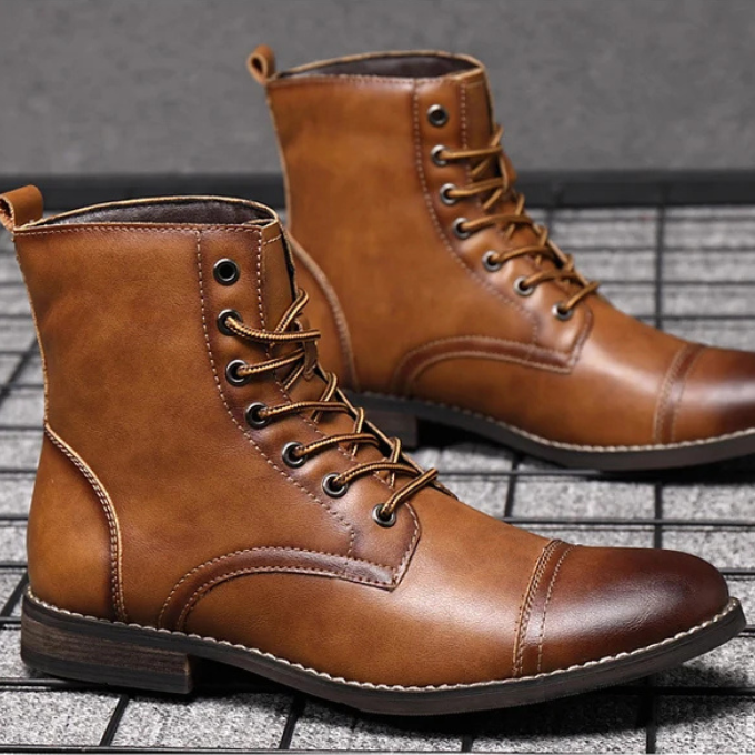 Pair of tan leather cap-toe boots with lace-up fastening, angled view