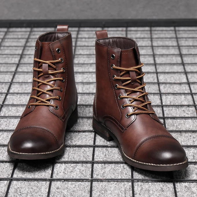 Dark brown leather boots with tan laces, front-facing pair on grid floor