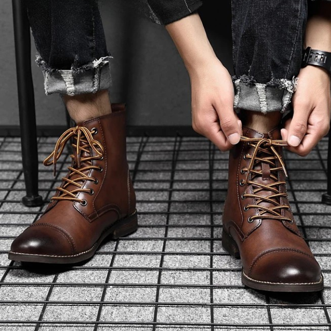 Man tying laces on a brown leather lace-up ankle boot