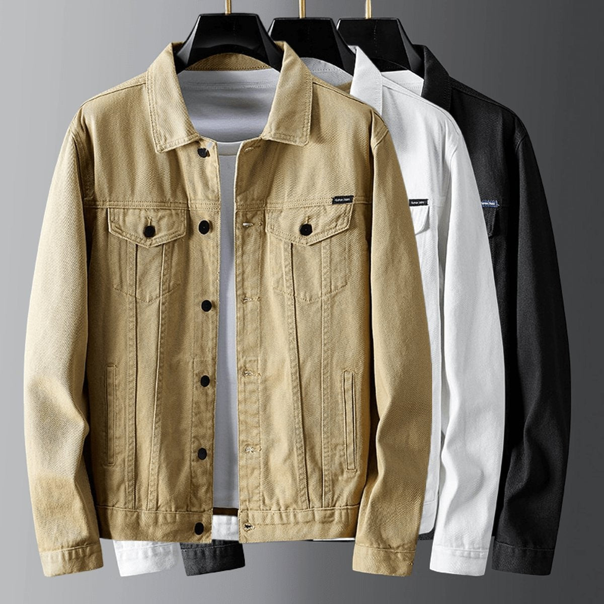Men's denim jackets in khaki, white and black on hangers with chest pockets
