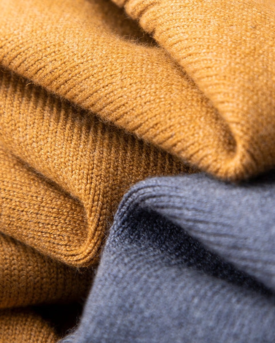Stacked mustard and slate blue jumpers highlighting ribbed knit texture