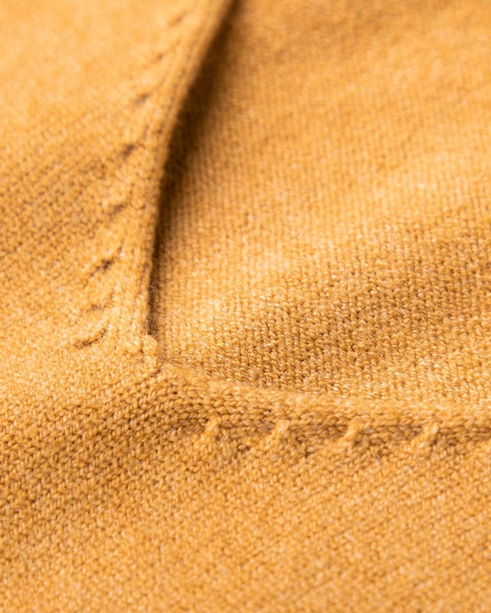 Close-up of mustard knitted jumper showing V-neck seam and fine knit texture