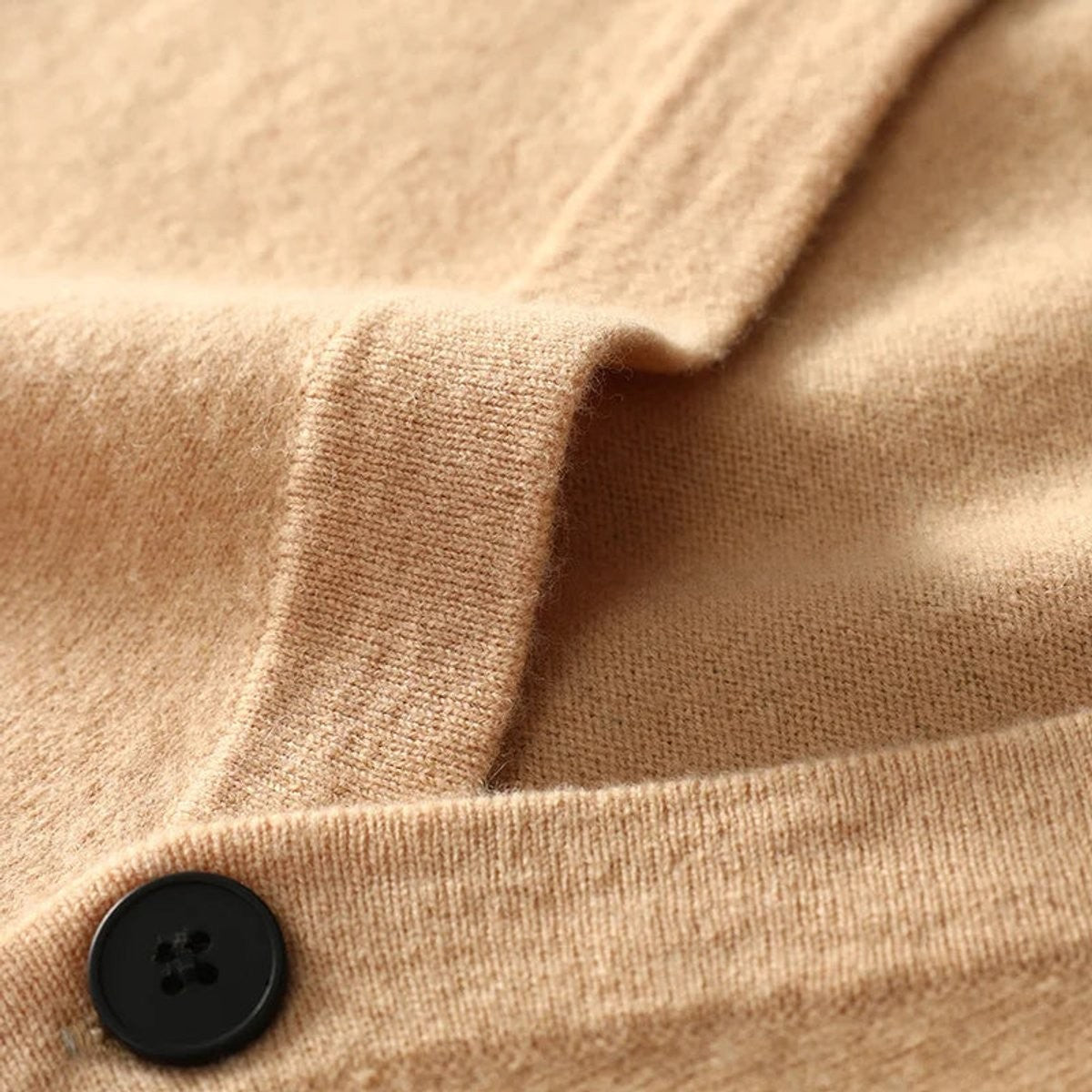 Close-up of camel knitted cardigan showing button fastening and ribbed cuff