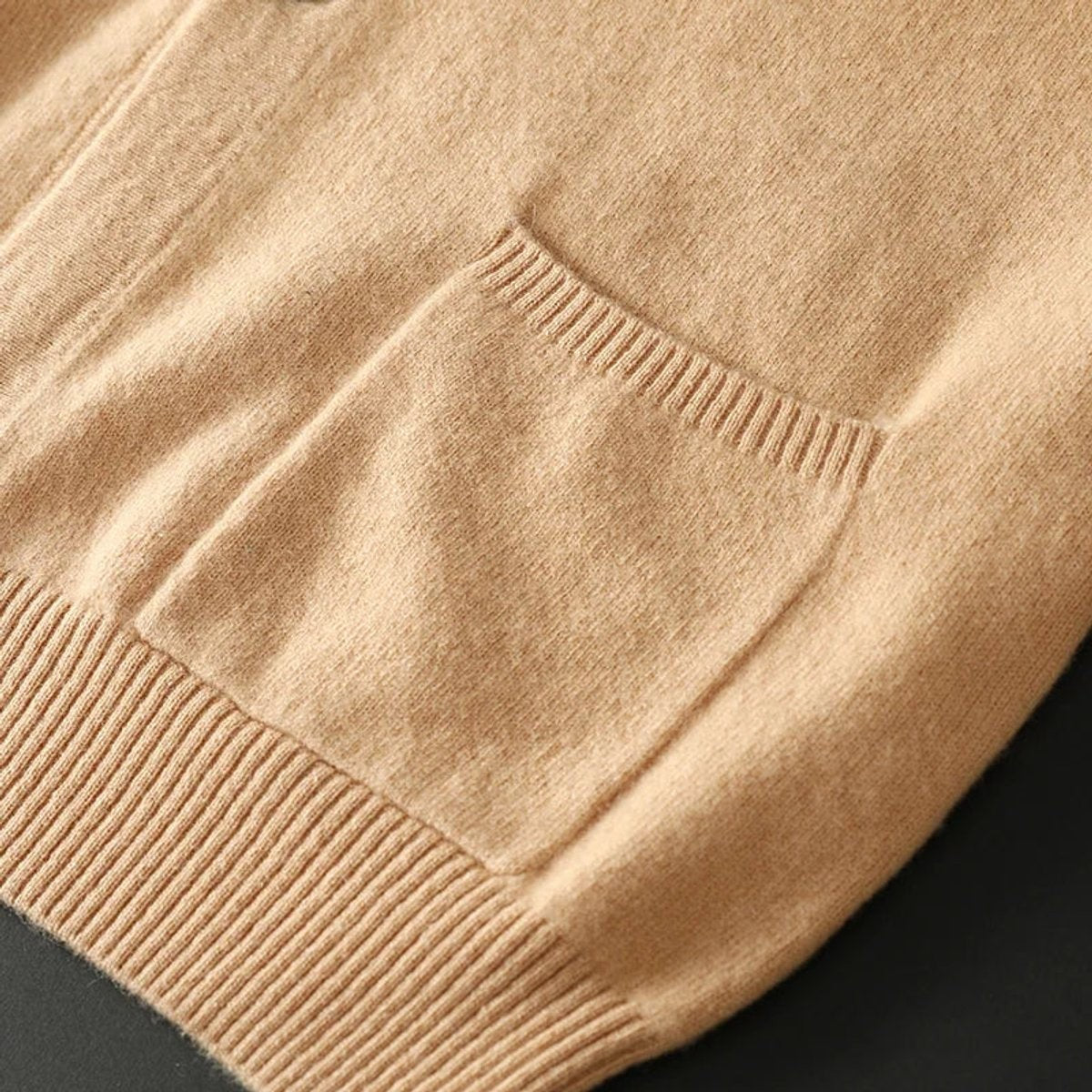 Detail shot of camel cardigan's patch pocket and ribbed knit texture