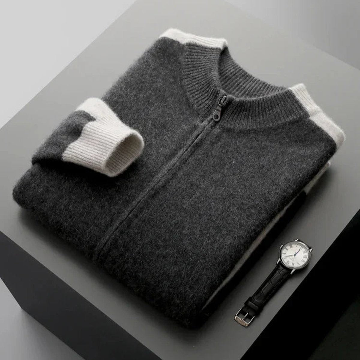 Navy cashmere zip cardigan folded with cream contrast cuffs beside a watch