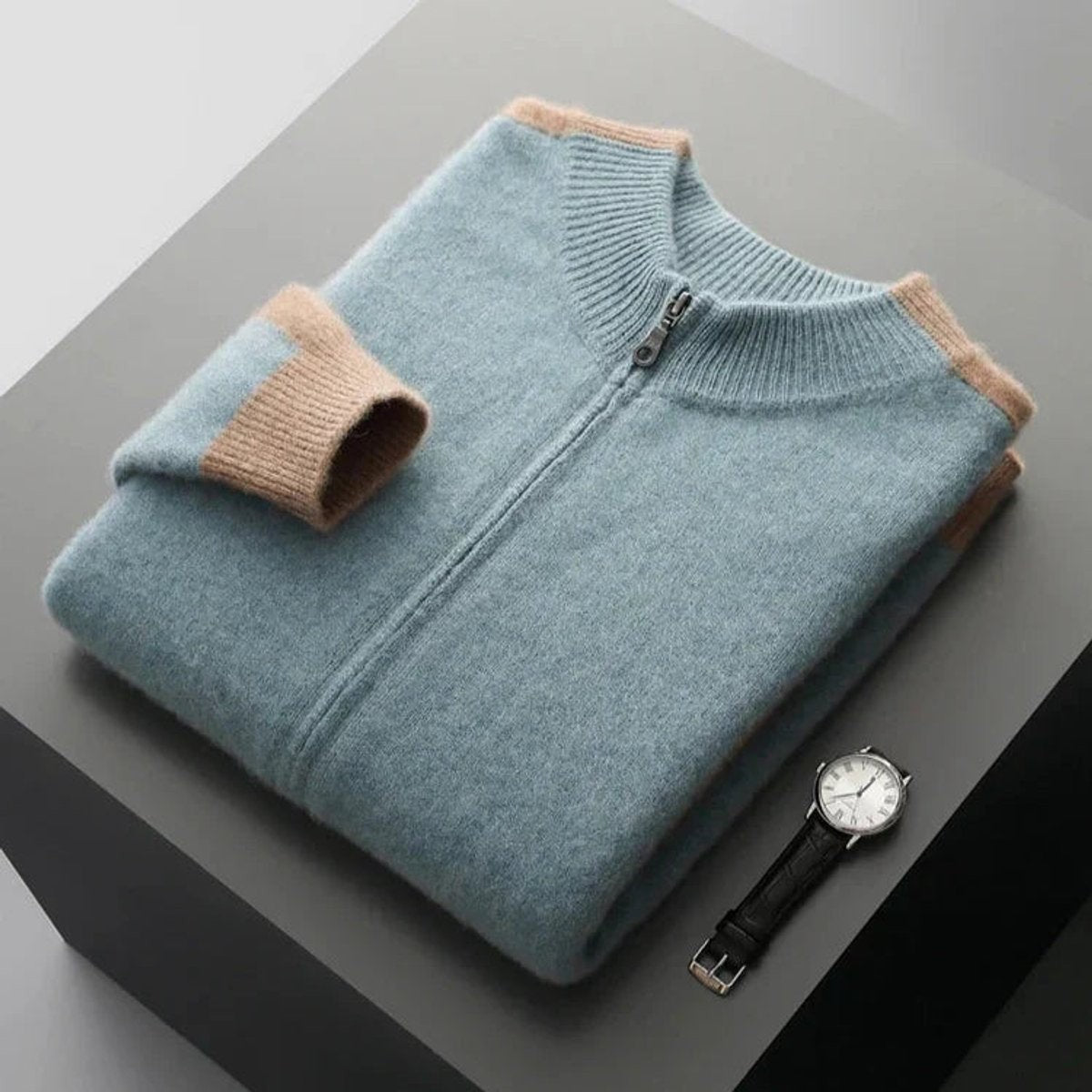Charcoal cashmere zip cardigan folded with cream ribbed cuffs and a wristwatch