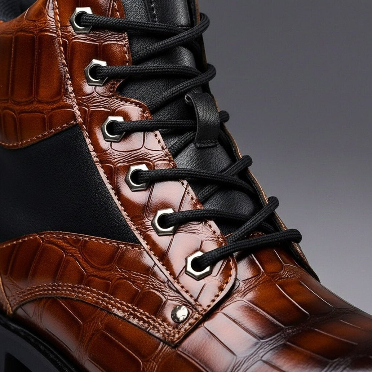 Close-up of lace-up eyelets on brown croc-embossed leather ankle boot