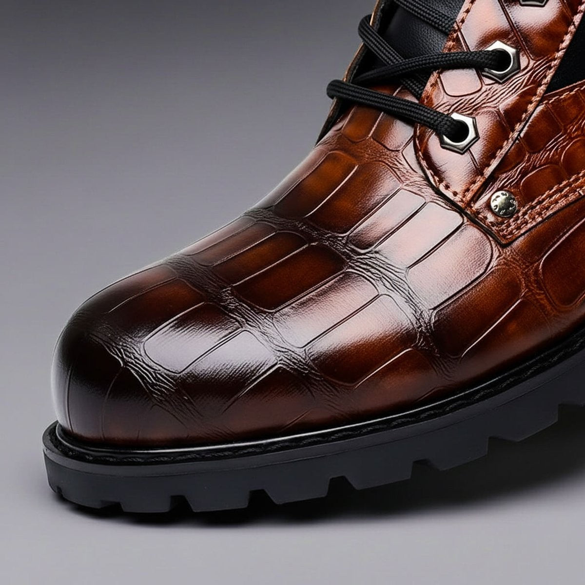 Close-up of toe cap and tread detailing on brown croc-embossed leather boot