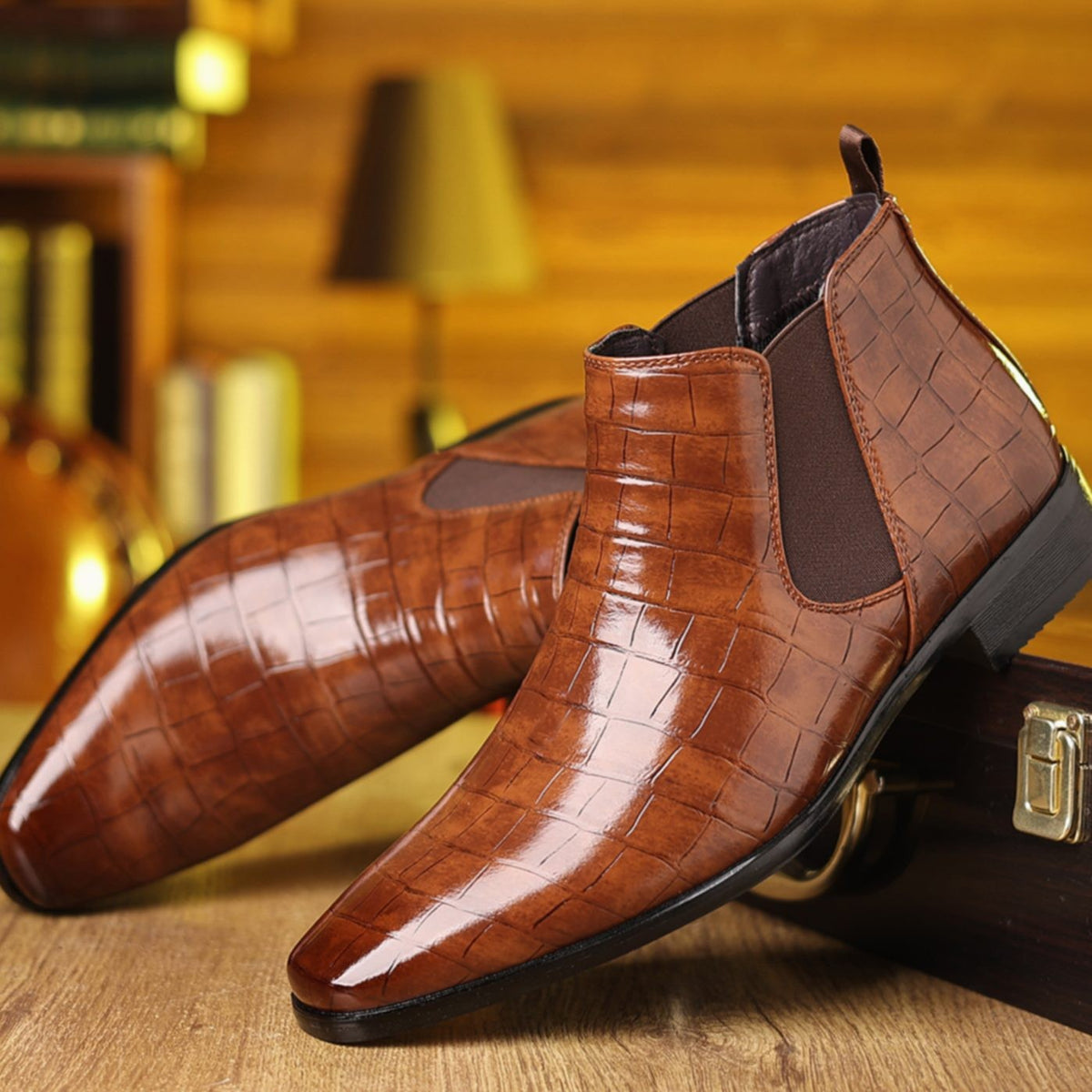 Pair of brown crocodile-effect leather Chelsea boots beside a briefcase