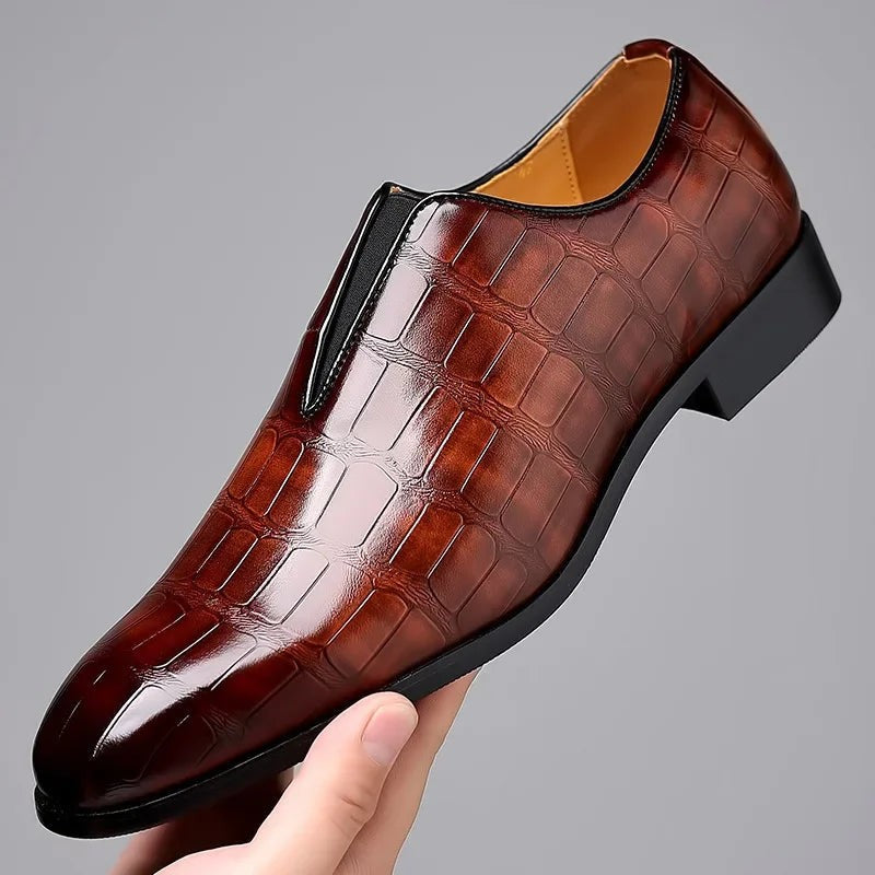 Hand holding burgundy croc-embossed leather loafer with elasticated side panel