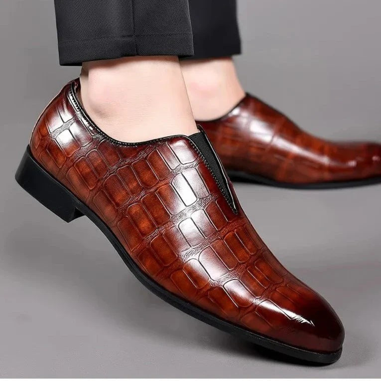 Model wearing burgundy crocodile-embossed leather loafers with tailored trousers