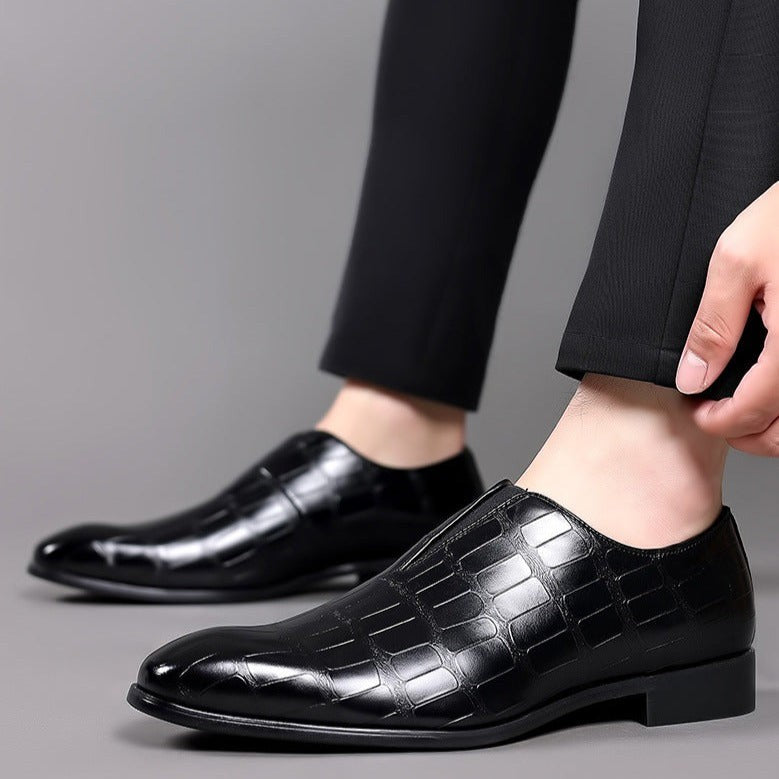 Pair of glossy burgundy crocodile-print leather slip-on shoes on dark surface