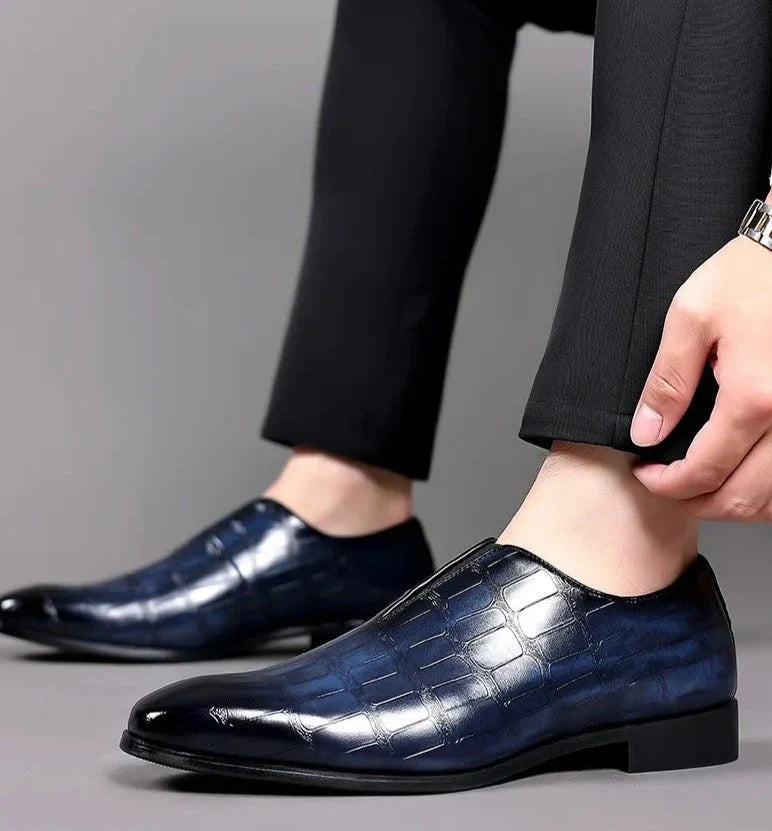 Model adjusting trouser hem above black croc-embossed leather dress shoe