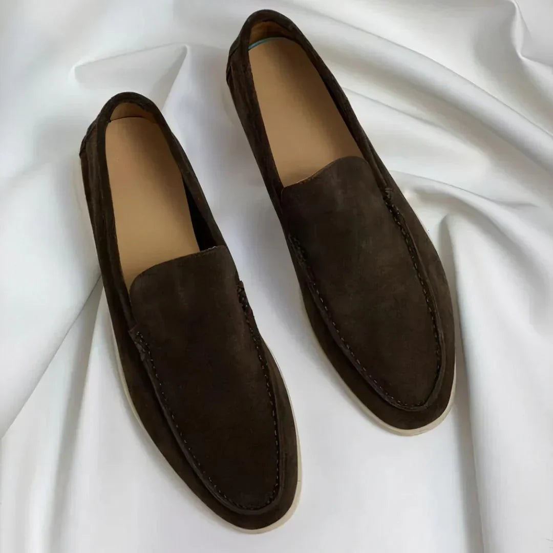 Dark brown suede loafers with white soles on white fabric