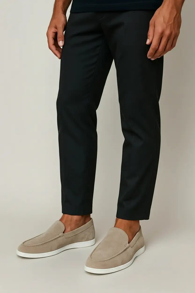 Model wearing taupe suede loafers styled with slim black trousers