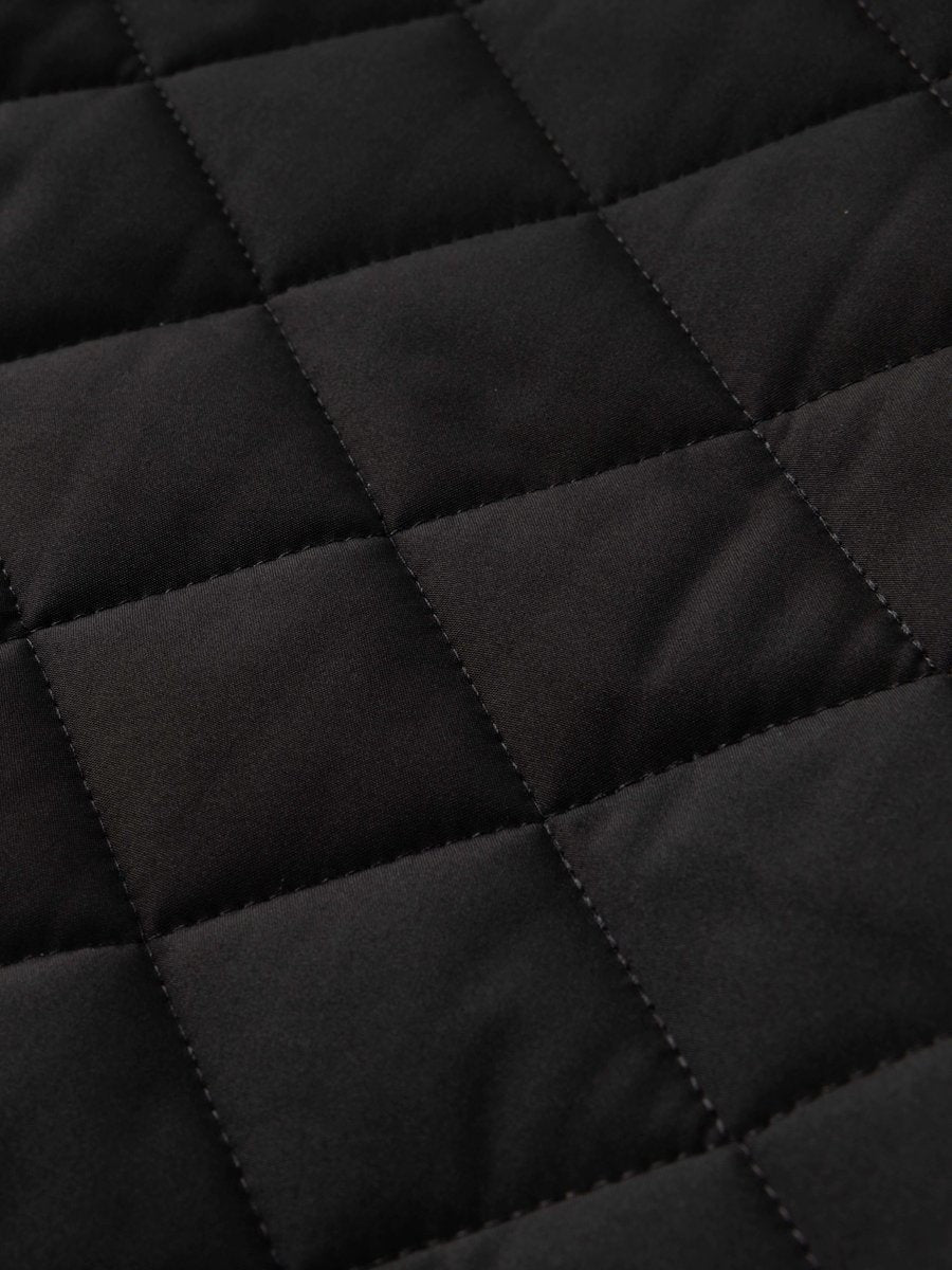 Close-up of black diamond-quilted fabric texture on fleece-lined bomber
