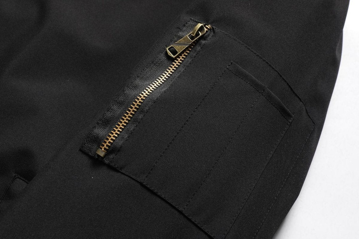 Detail shot of black bomber jacket's zipped sleeve pocket with brass zip