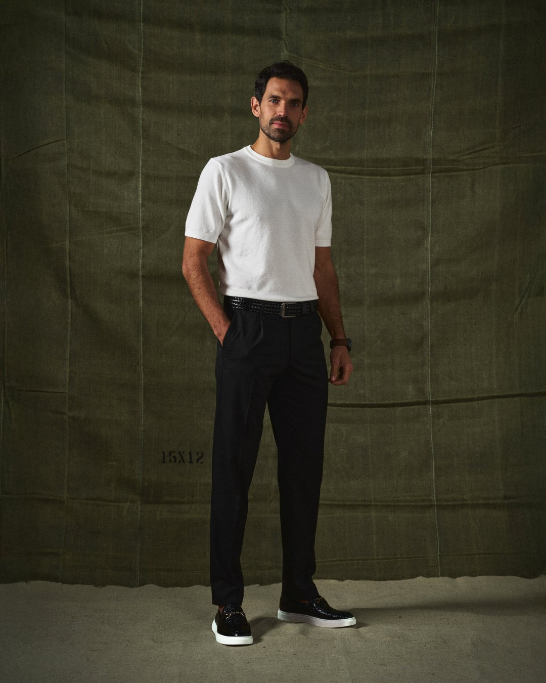 Man wearing white knitted t-shirt, black trousers and croc-effect leather loafers