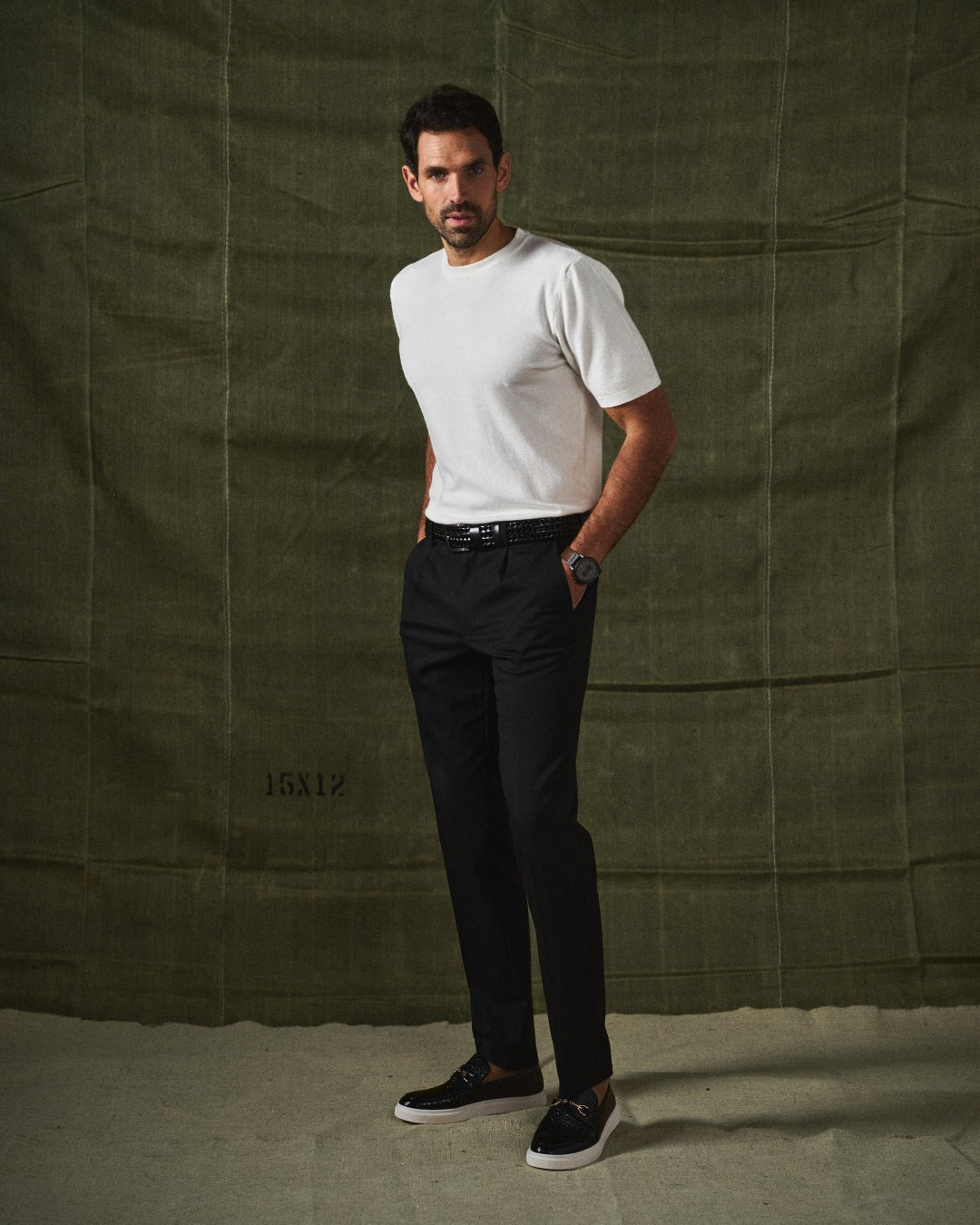 Full-length shot of man in black loafers, white knit tee and black trousers