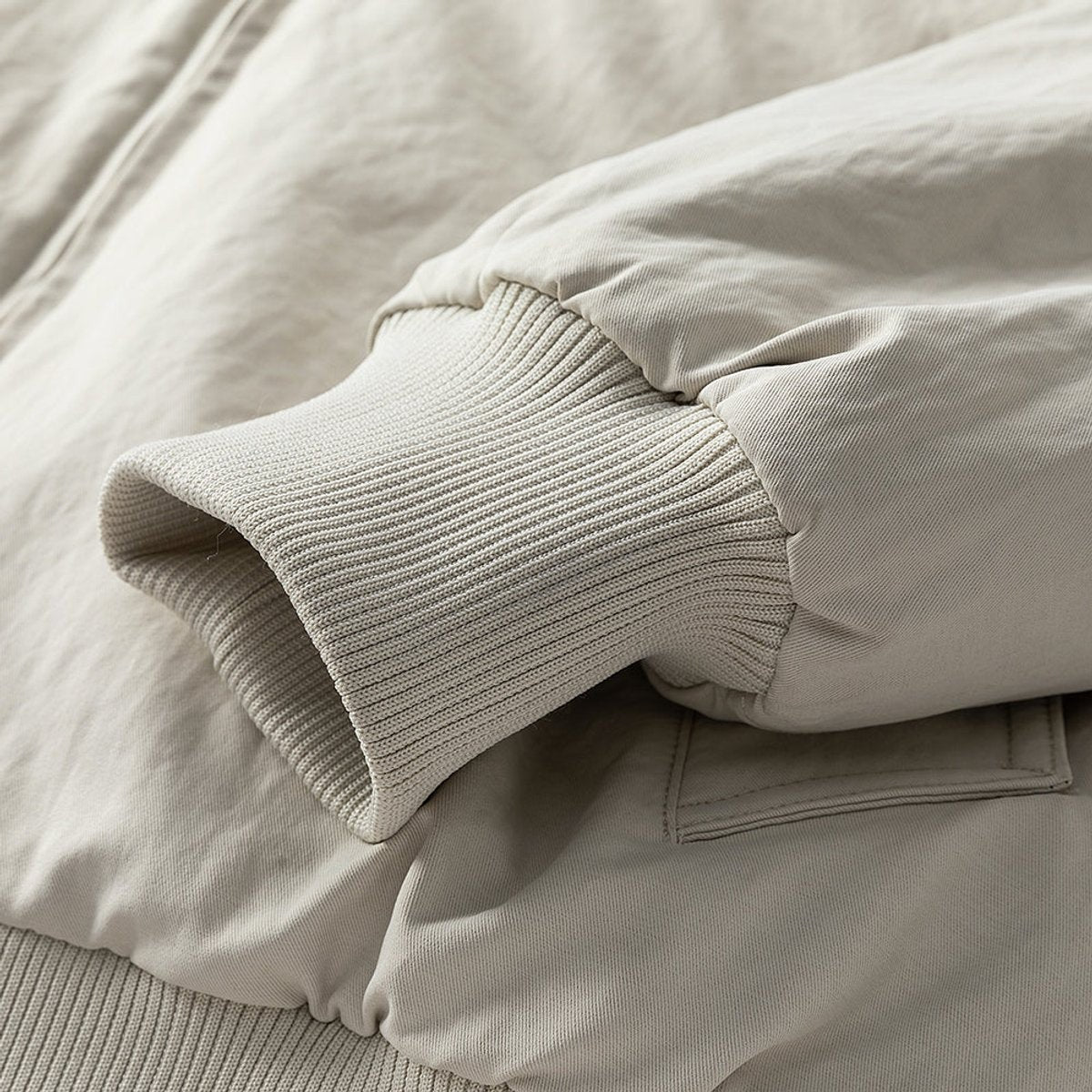 Close-up of ribbed cuff detail on cream faux fur-lined bomber jacket