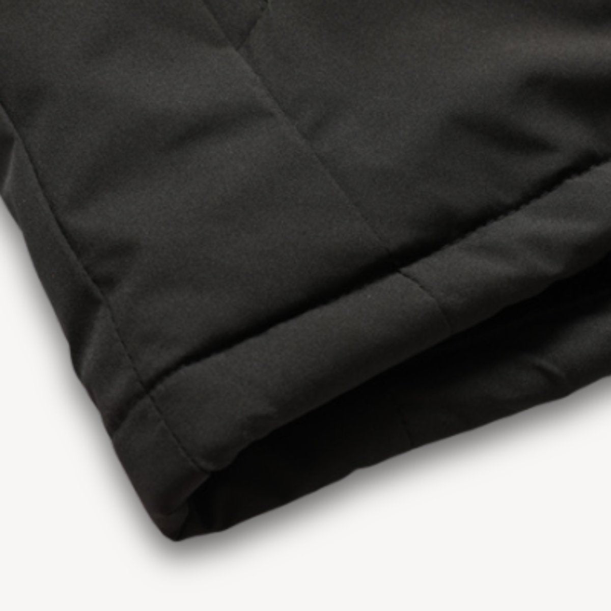 Close-up of black jacket hem showing quilted stitched panel detail