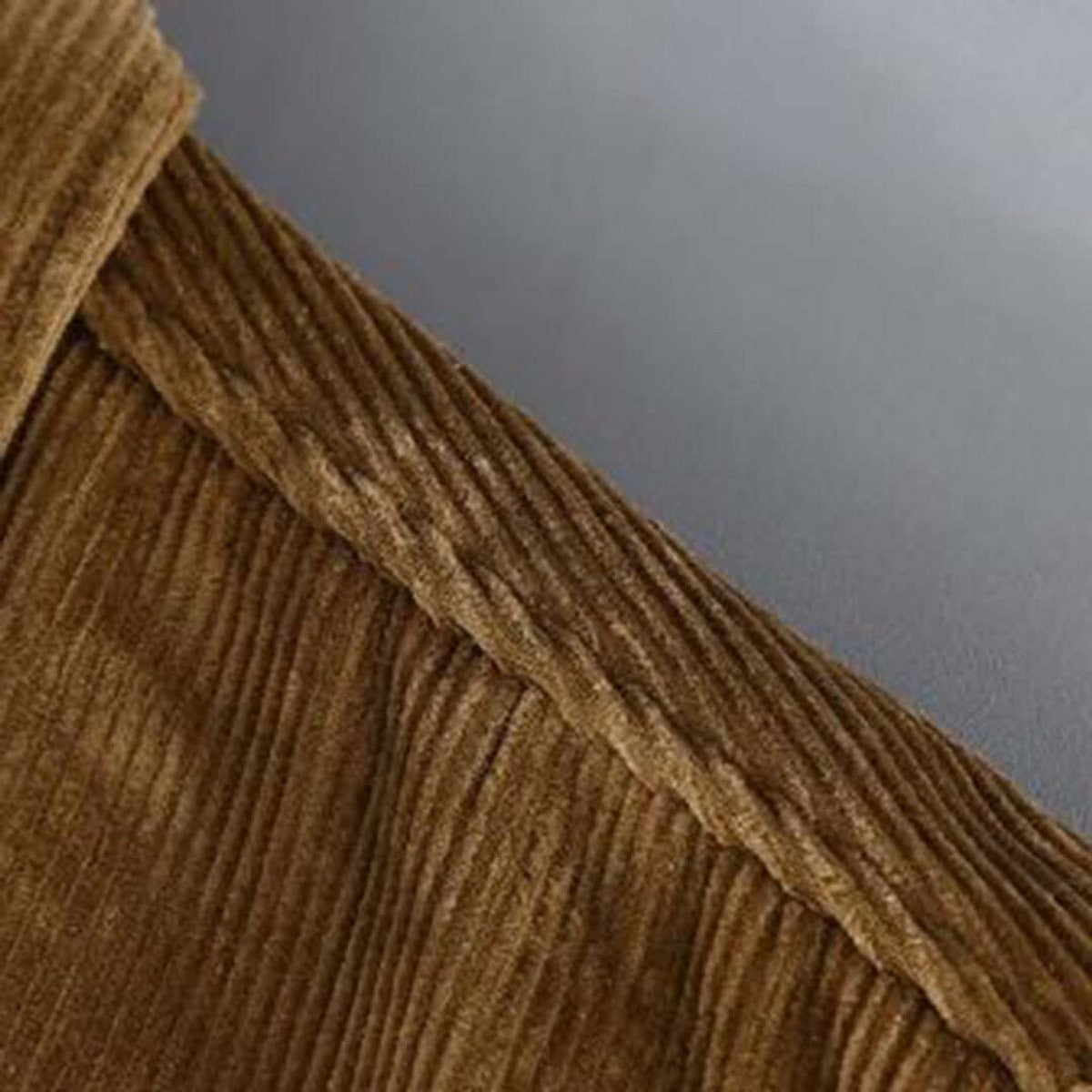 Textured corduroy fabric close-up showing ribbed weave in camel tone