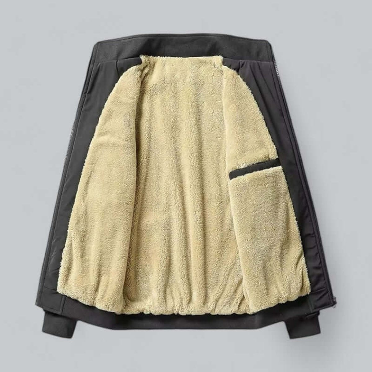 Black fleece-lined bomber jacket laid flat showing sherpa interior and zip pocket
