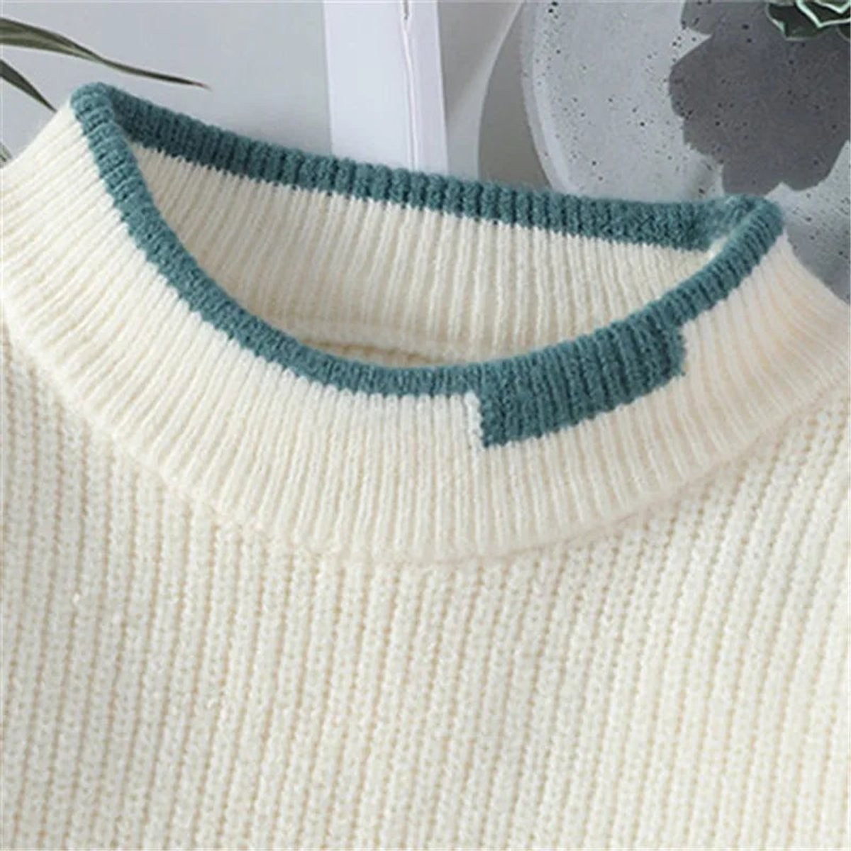 Close-up of cream jumper collar with contrasting teal ribbed trim