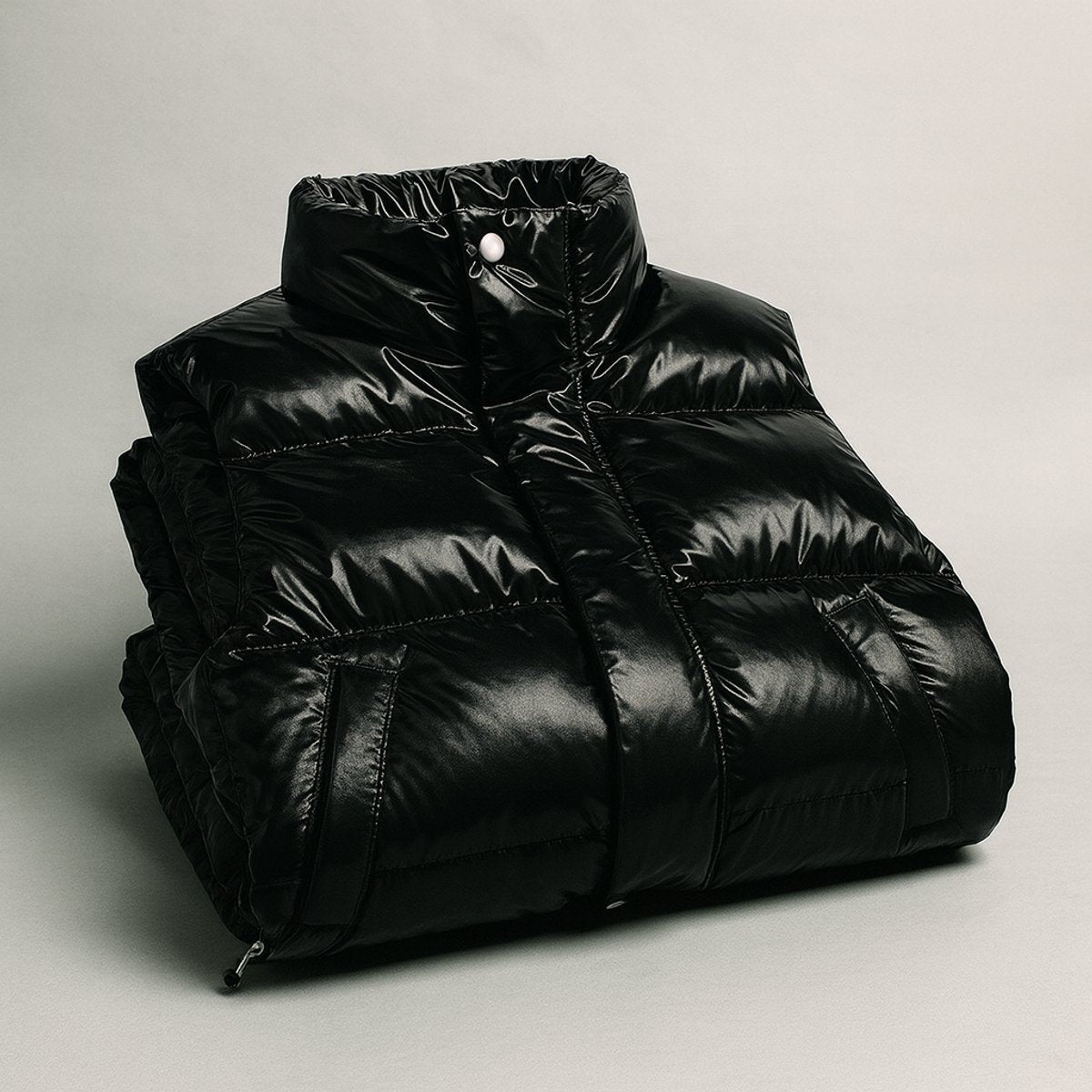 Folded black puffer vest with glossy quilted finish