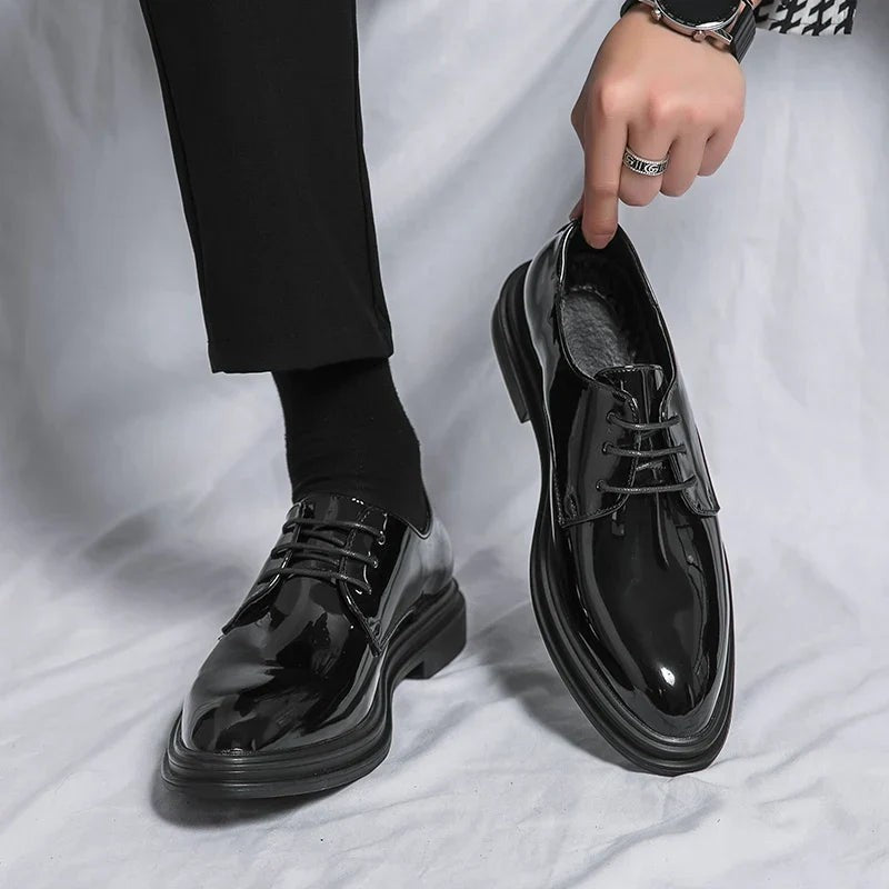 Man holding glossy black patent Derby shoe with lace-up front