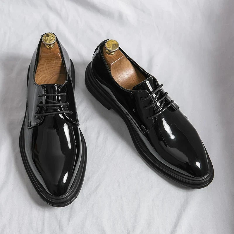 Pair of black patent leather Derby shoes displayed with wooden shoe trees