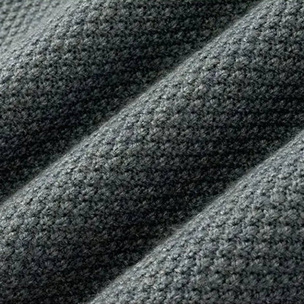 Macro texture shot of dark grey jacquard-knit fabric on ribbed jumper