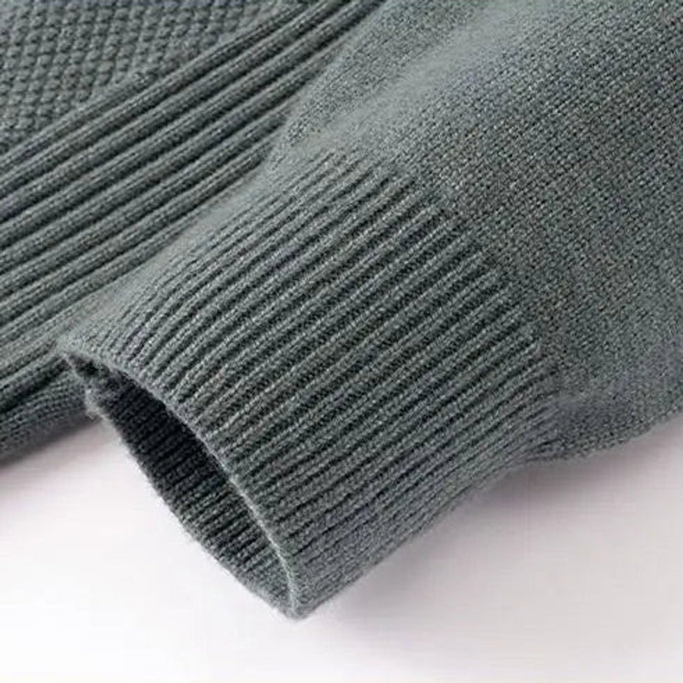 Close-up of grey-green ribbed cuff and textured knit fabric on jumper