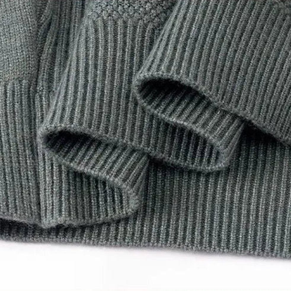 Folded ribbed sleeve detail on grey-green mock-neck knit pullover