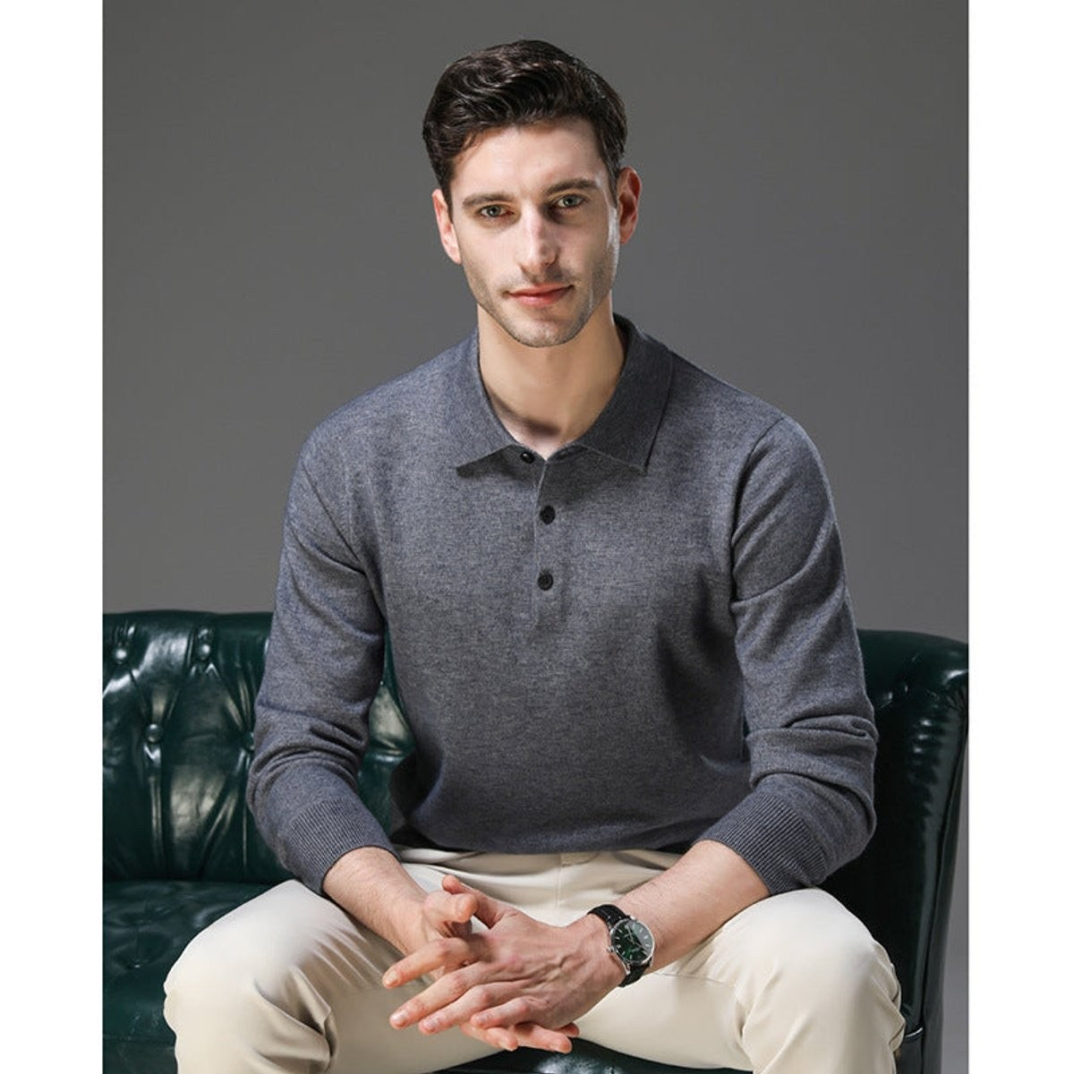 Man seated wearing grey long-sleeve knitted polo jumper on leather sofa