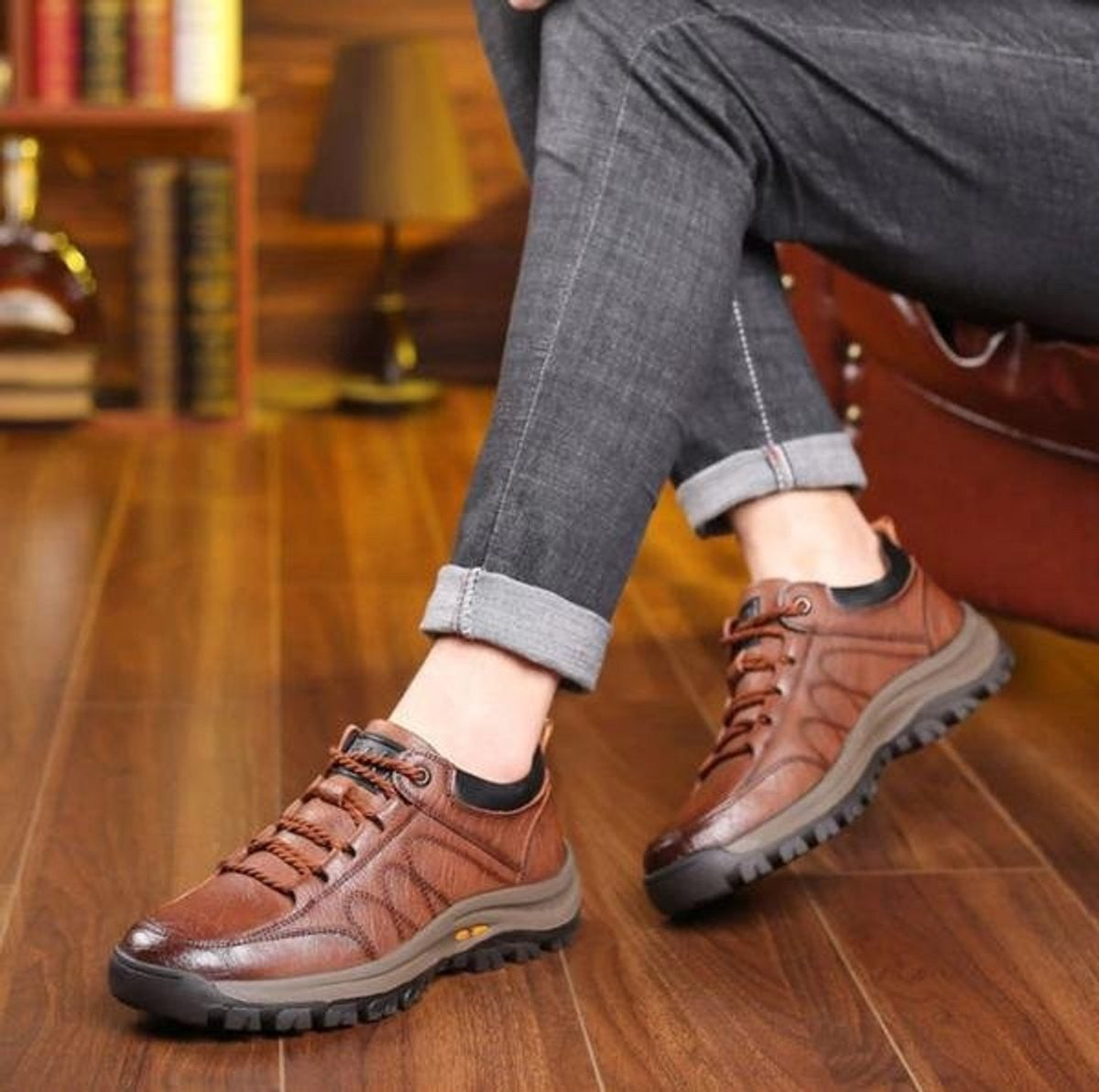 Man seated wearing tan leather lace-up casual shoes with jeans