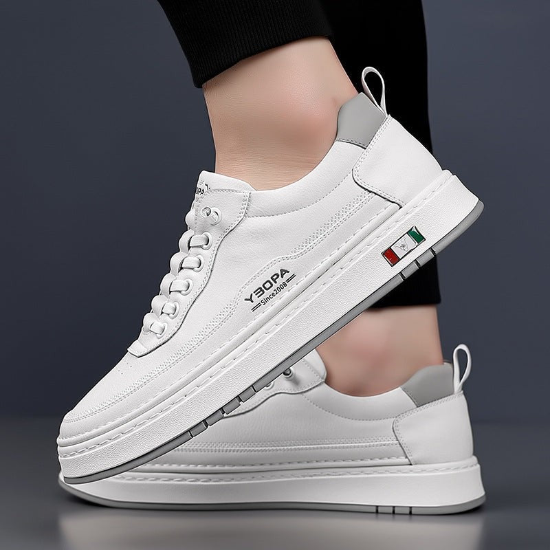 White leather trainers displayed together, one held by hand