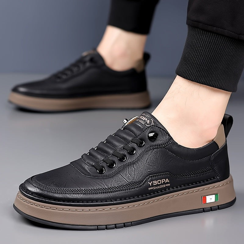 Black leather trainer held by hand against grey background