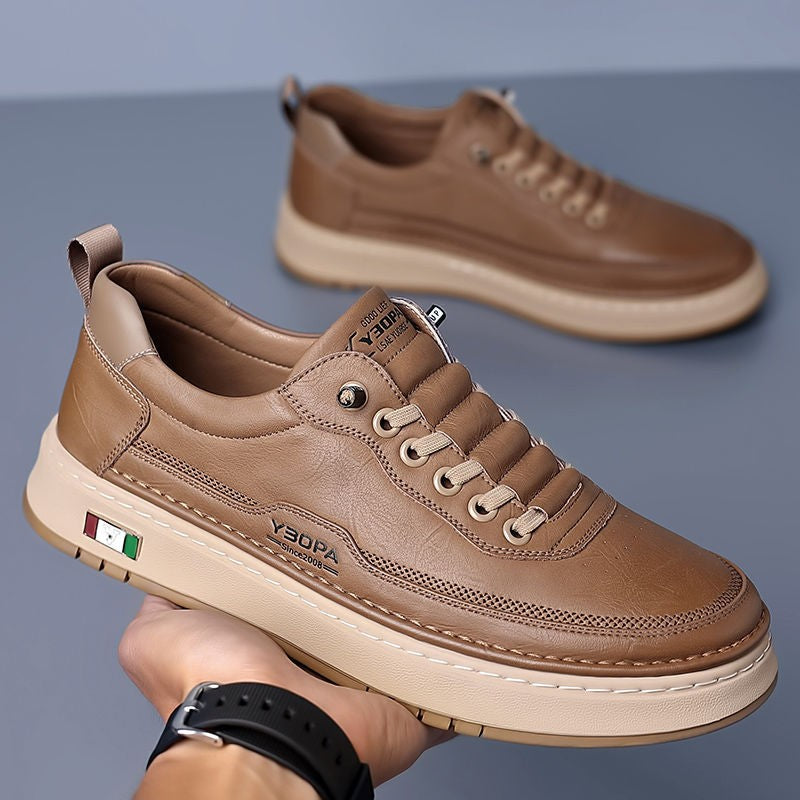Camel leather trainer held by hand, showcasing sole grip