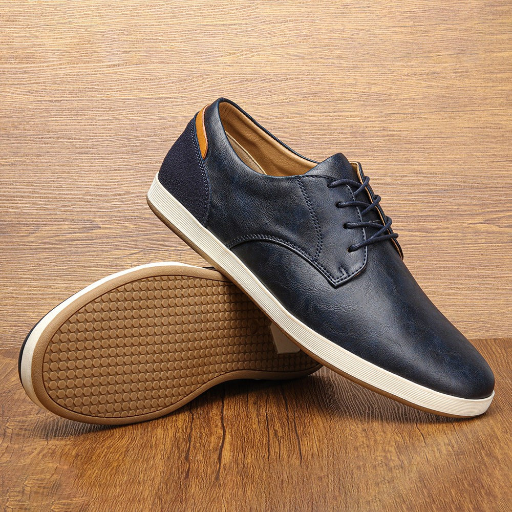 Navy leather lace-up trainer balanced on its sole showing tan tread pattern