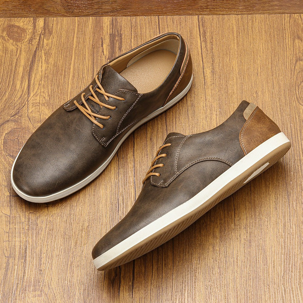 Brown leather lace-up trainers with tan laces displayed on wooden surface