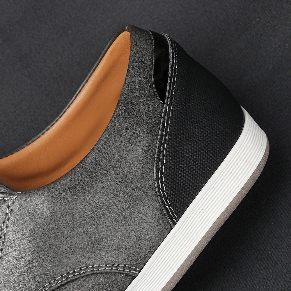 Close-up of stitched heel detail on grey and black leather trainer